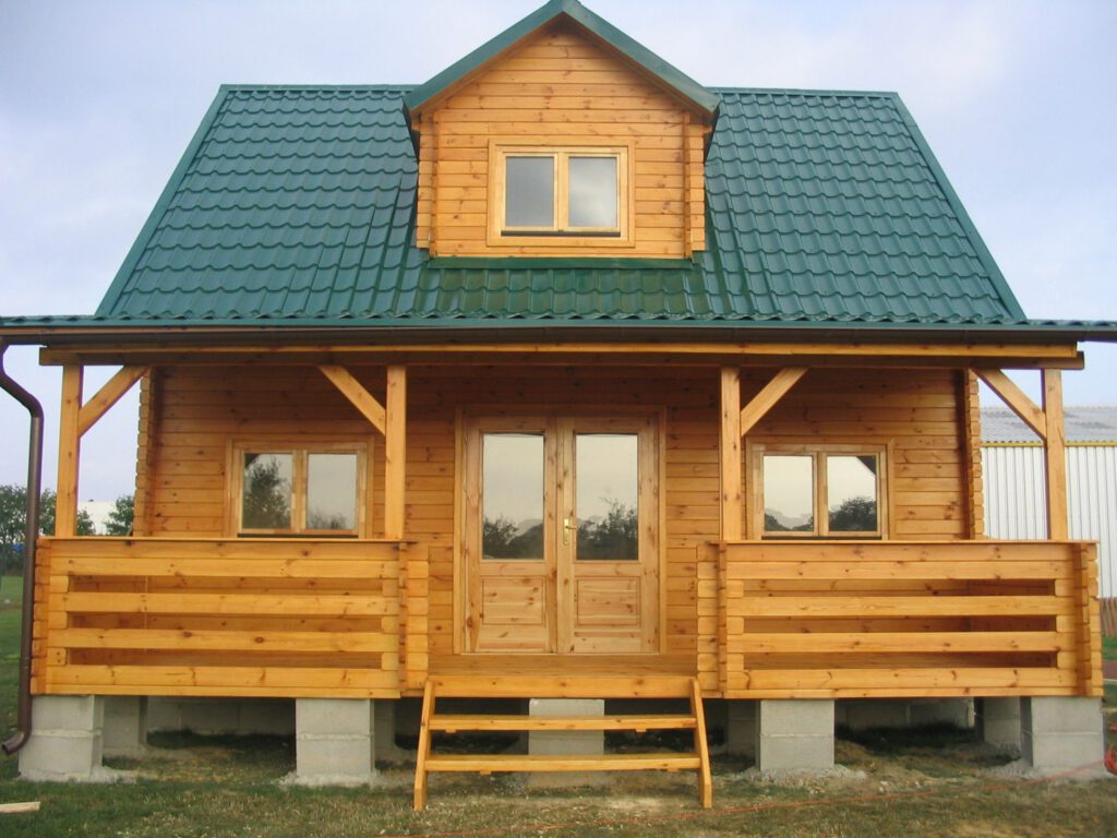 Dom drewniany z tarasem postawiony na bloczkach betonowych